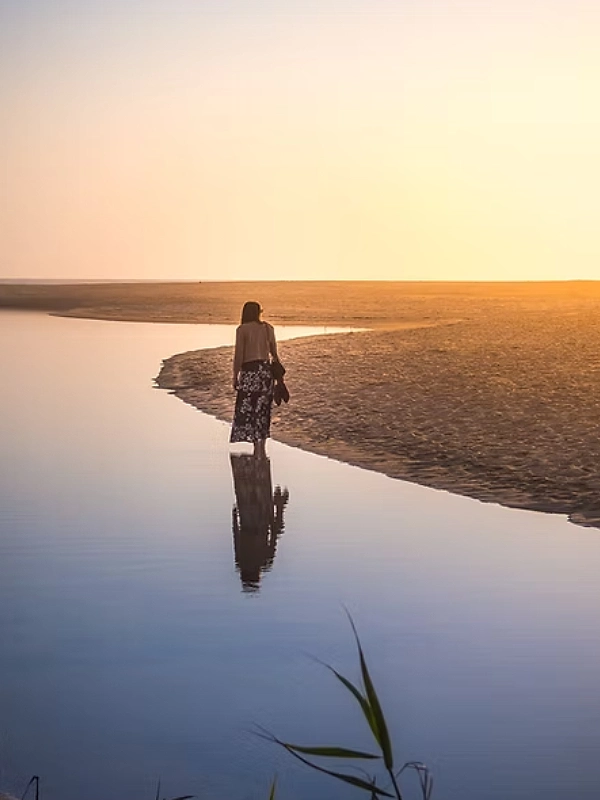 Personne marchant au bord de l'eau au coucher du soleil